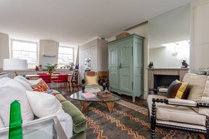 Ein Wohnzimmer mit Sofa, Sesseln, Couchtisch und Kamin.
