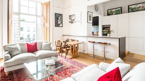 Ein modernes Wohnzimmer mit einer Couch, einem Glastisch und einem Essbereich mit Holztisch und Stühlen.