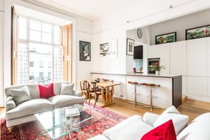 Ein modernes Wohnzimmer mit einer Couch, einem Glastisch und einem Essbereich mit Holztisch und Stühlen.