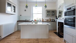 A kitchen with a central island, white cabinetry, a built-in oven, and pendant lighting. - Westbourne Grove VIII (London)