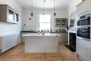 A kitchen with a central island, white cabinetry, a built-in oven, and pendant lighting. - Westbourne Grove VIII (London)