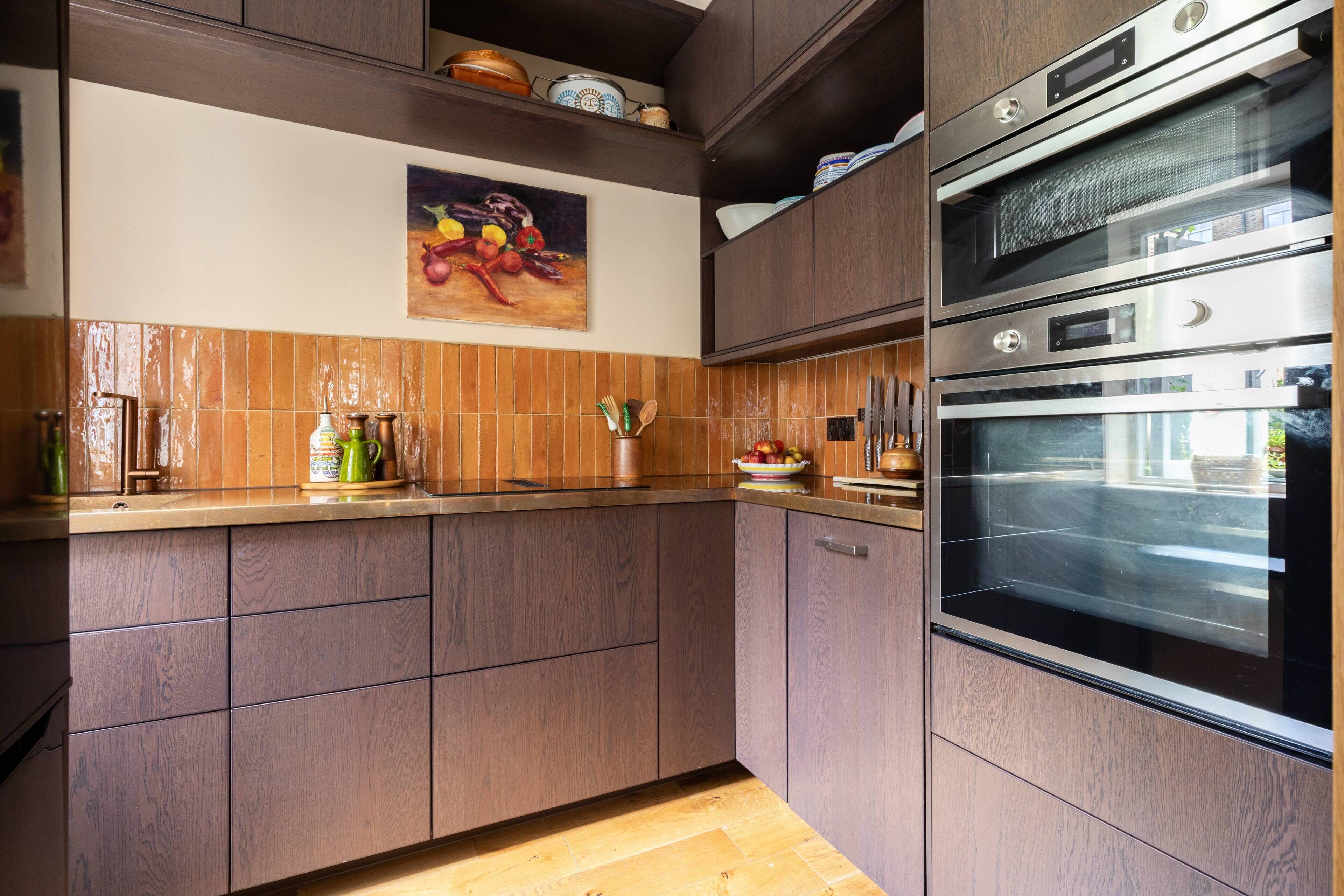 A kitchen with wooden cabinets, a stainless steel oven, and a tiled backsplash.