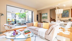 Ein modernes Wohnzimmer mit Glastisch, gestreifter Couch und Blick ins Freie.