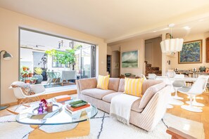 A modern living room with a glass coffee table, striped sofa, and a view of the outdoors. - Wyndham Mews III - Three Bedroom House, Sleeps 6 (London)