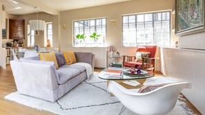 Ein Wohnzimmer mit Sofa, Sessel, Couchtisch und einem Essbereich mit Tisch und Stühlen.