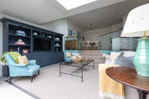 Ein Wohnzimmer mit einer Couch, einem Sessel, einem Couchtisch und einem Bücherregal.
