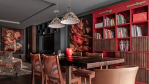 Ein Essbereich mit einem Holztisch, Stühlen und einem roten Bücherregal voller Bücher.