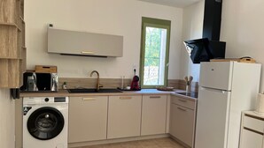 Une cuisine compacte équipée d’un lave-linge, d’un four encastré et d’une fenêtre offrant une vue agréable.