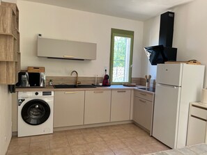 Una cocina compacta con lavadora, horno integrado y ventana con vistas.