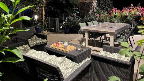 Une terrasse extérieure aménagée avec des meubles en osier, une table et un parasol.
