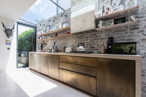 Eine moderne Küche mit Backsteinwand, Holzregalen und einem großen Fenster.