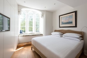 Ein Schlafzimmer mit Bett, einem Fenster mit Blick, einem gerahmten Bild an der Wand und einem Fernseher.