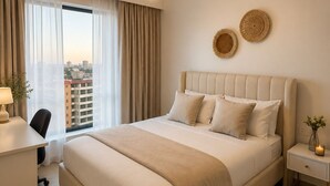 Ein Hotelzimmer mit einem großen Bett, einem Schreibtisch, einem Sessel, einem Nachttisch und einem Fenster mit Vorhängen.