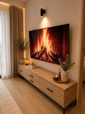 A modern living room with a large flat-screen TV mounted on the wall, a wooden console table with a vase and candles, and a potted plant. - 2 bedroom south c,Nairobi west near airport.Nexgen mall (Nairobi)