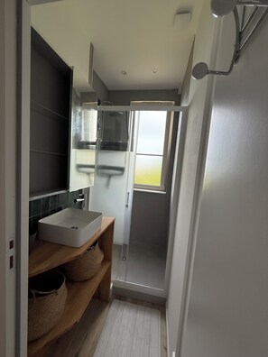 Une salle de bain moderne avec une douche, un lavabo et une fenêtre.