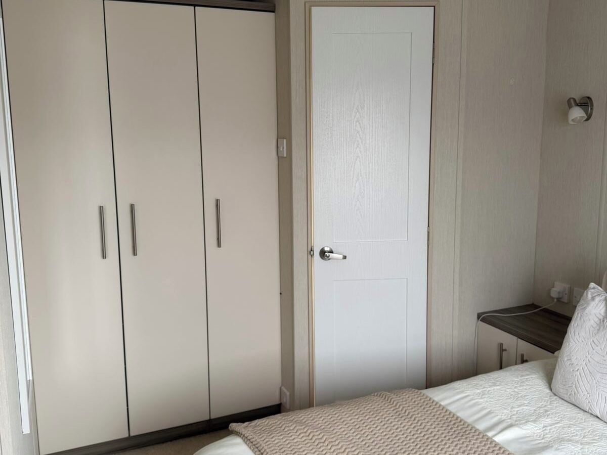 Een slaapkamer met een bed, een kledingkast, een deur en een nachtkastje.