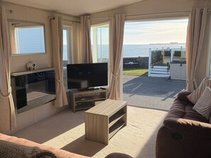A living room with a TV, a wooden coffee table, and a sofa. - Trecco Bay Holiday Park, Porthcawl (Porthcawl)