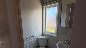 Pieni kylpyhuone, jossa on wc, ikkuna, patteri ja pesuallas.