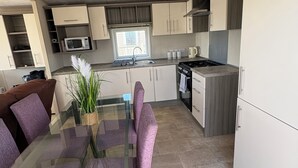 Moderni keittiö, jossa on lasinen ruokapöytä, mikroaaltouuni ja liesi.