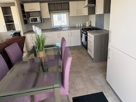 Una cocina moderna con una mesa de comedor de vidrio, un microondas y una estufa.