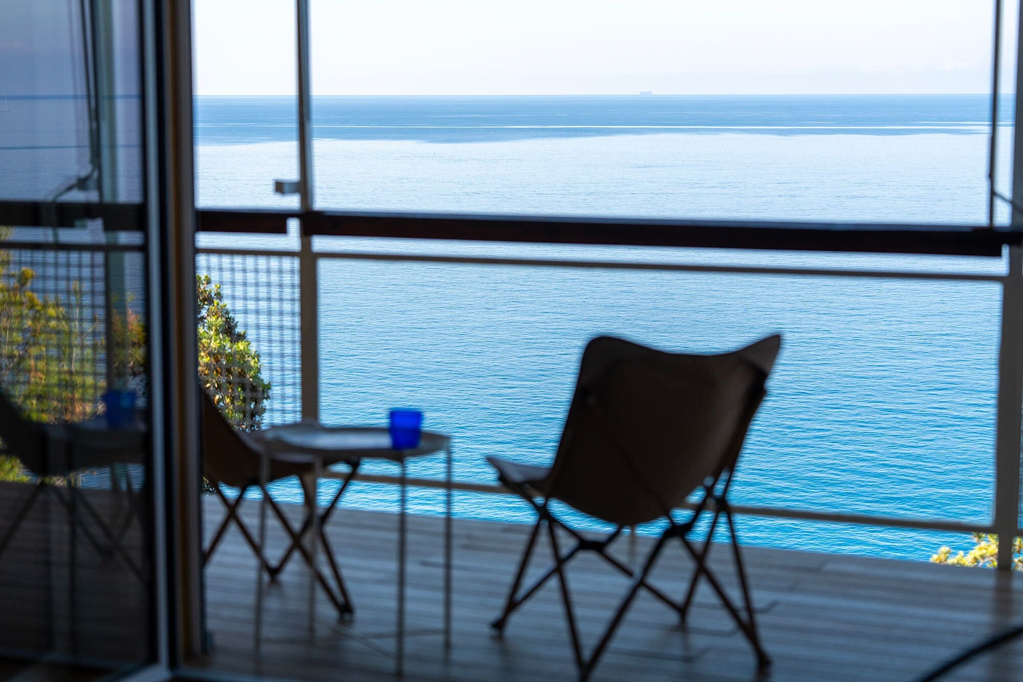 Un balcon avec vue sur la mer, deux chaises et une petite table.