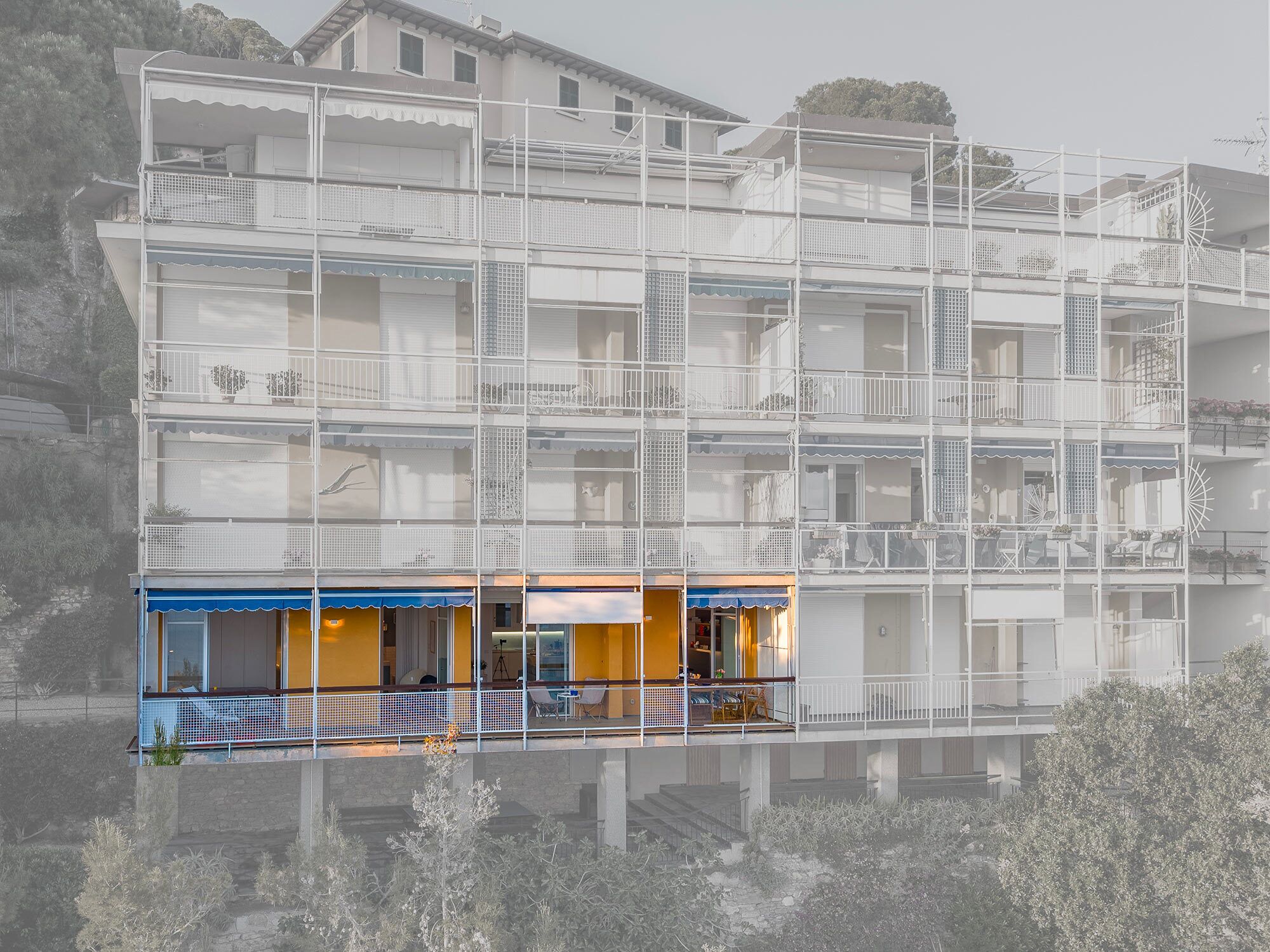 Un immeuble à plusieurs étages doté de balcons, d’un commerce situé au rez-de-chaussée et d’un élément décoratif aquatique réfléchissant à l’avant.
