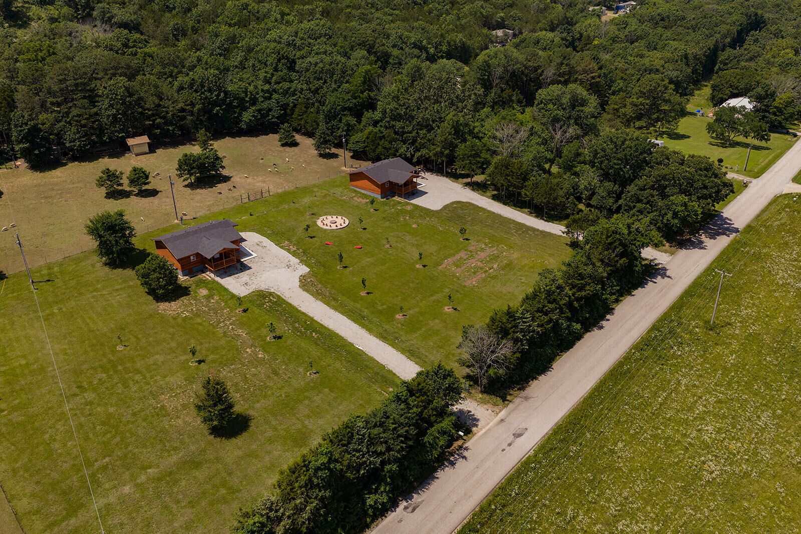 An aerial view of a property with two buildings, a fenced pasture, and a road.