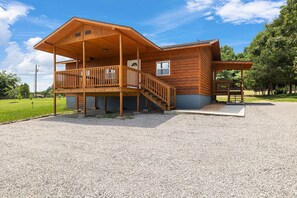 Eine Holzhütte mit Balkon, überdachter Veranda und einem Schotterweg.