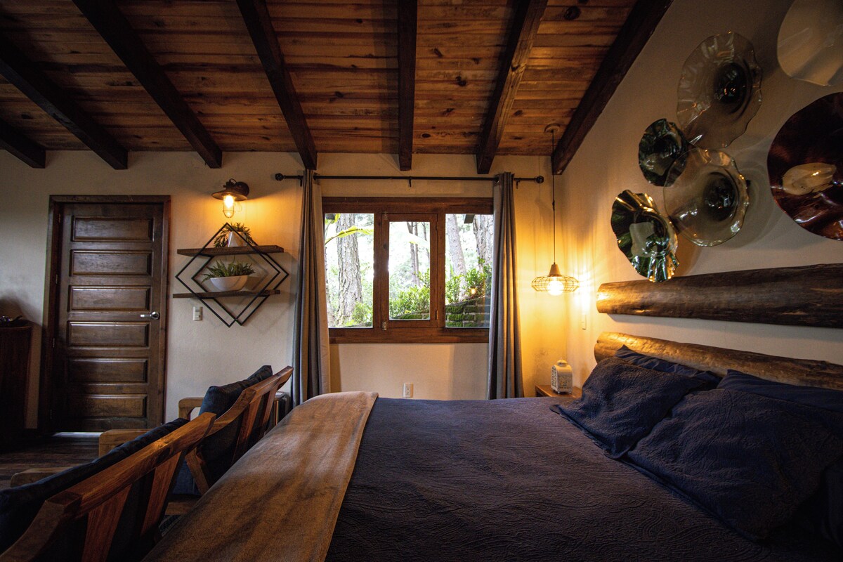 A wooden-framed room with a bed, a desk, and a window.