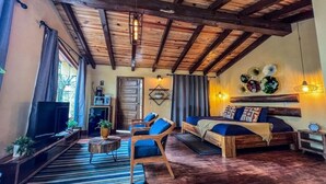 Una habitación rústica con techo de madera, un sofá, un televisor y una mesa de comedor.