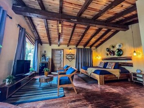 A rustic room with a wooden ceiling, a sofa, a TV, and a dining table. - Cabañas VIP Mazamitla (Mazamitla)
