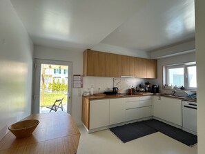 A modern kitchen with wooden cabinets, a black countertop, and a view of the outside. - The Blue House Estoril, Pergola and Lounge - 5 mins from the beachand woodland (Estoril)