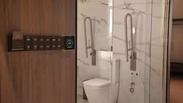 A modern bathroom with a toilet, bidet, and glass shower enclosure.