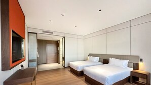 Habitación de hotel moderna con dos camas, un escritorio y un espejo.