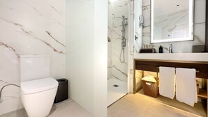 Un baño con inodoro, ducha y tocador con espejo.