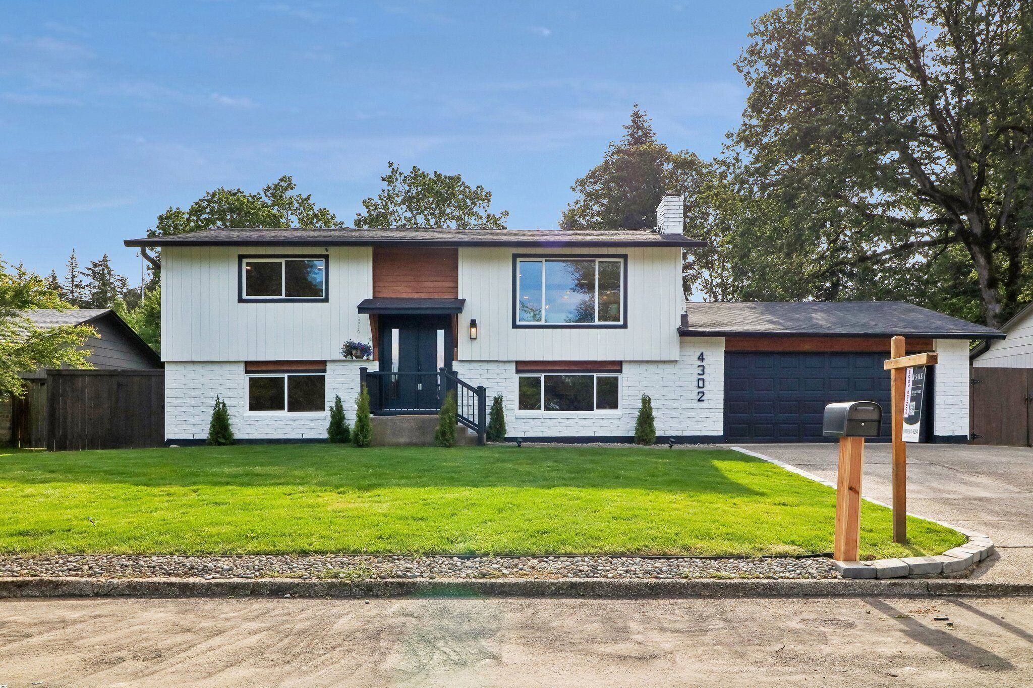 A two-story house with a front garage, a well-maintained lawn, and a mailbox.