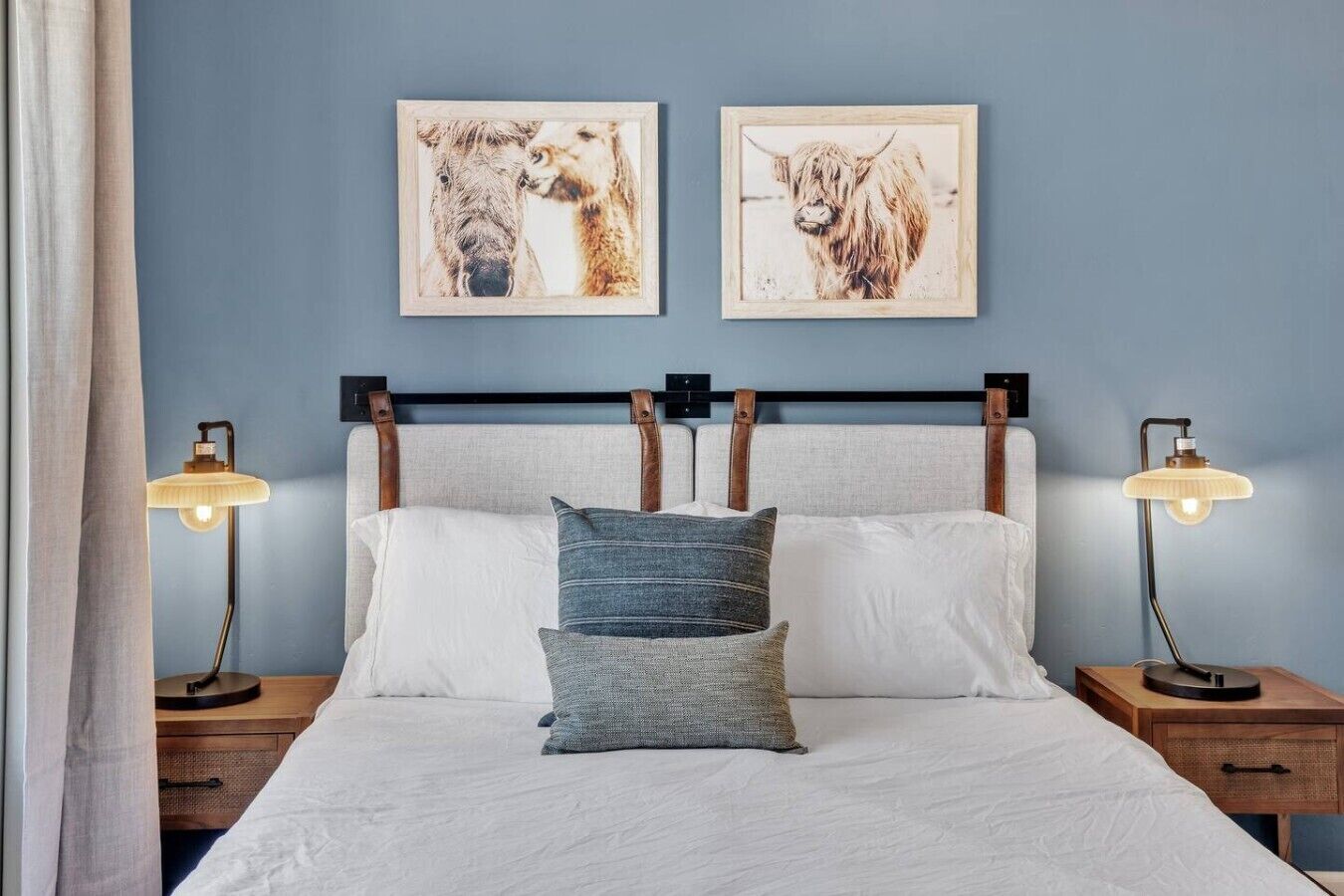 Een bed met witte lakens, twee kussens en twee bedlampjes.