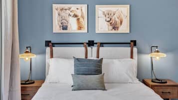 Een bed met witte lakens, twee kussens en twee bedlampjes.
