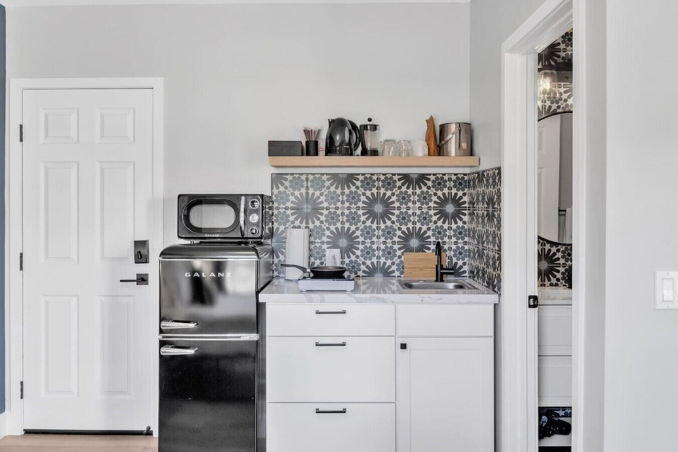 A compact kitchen with a microwave, stove, and a shelf above the countertop.