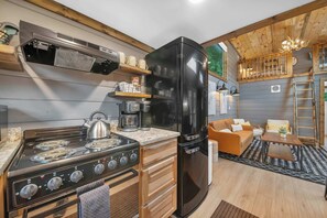 A compact kitchen with a stove, refrigerator, and coffee maker. - 3 Cabins, Sleeps 18 - Private Hot Tubs, Near Chatt (Chattanooga)