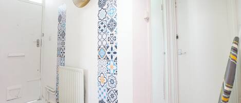 A hallway with patterned wallpaper, a radiator, a door, and a striped object leaning against the wall.