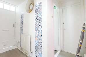 A hallway with patterned wallpaper, a radiator, a door, and a striped object leaning against the wall. - 3BR Flat in King`s Cross, St. Pancras Area - 10 minutes walk to tube (London)