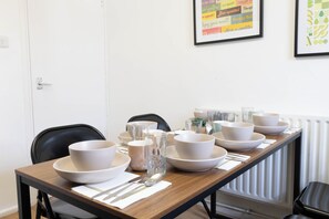 A dining table set with bowls, glasses, and cutlery, chairs, and framed artwork on the wall. - 3BR Flat in King`s Cross, St. Pancras Area - 10 minutes walk to tube (London)