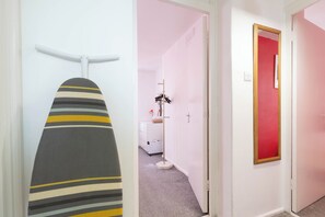 A hallway with a striped ironing board, a coat rack, and a red-framed mirror. - 3BR Flat in King`s Cross, St. Pancras Area - 10 minutes walk to tube (London)