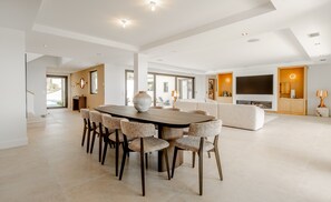 A spacious living area with a large dining table, comfortable seating, a sofa, a TV, and a fireplace. - Superb villa with swimming pool in a secure estate close to the beach and town center (Sainte-Maxime)