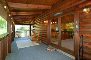 Eine Holzblockhütte mit Veranda, Schaukelstühlen und einem Schild mit der Aufschrift 'Erinnerungen entstehen hier'.