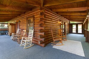 Eine Blockhütte mit Veranda, Schaukelstühlen und einem Teppichboden.