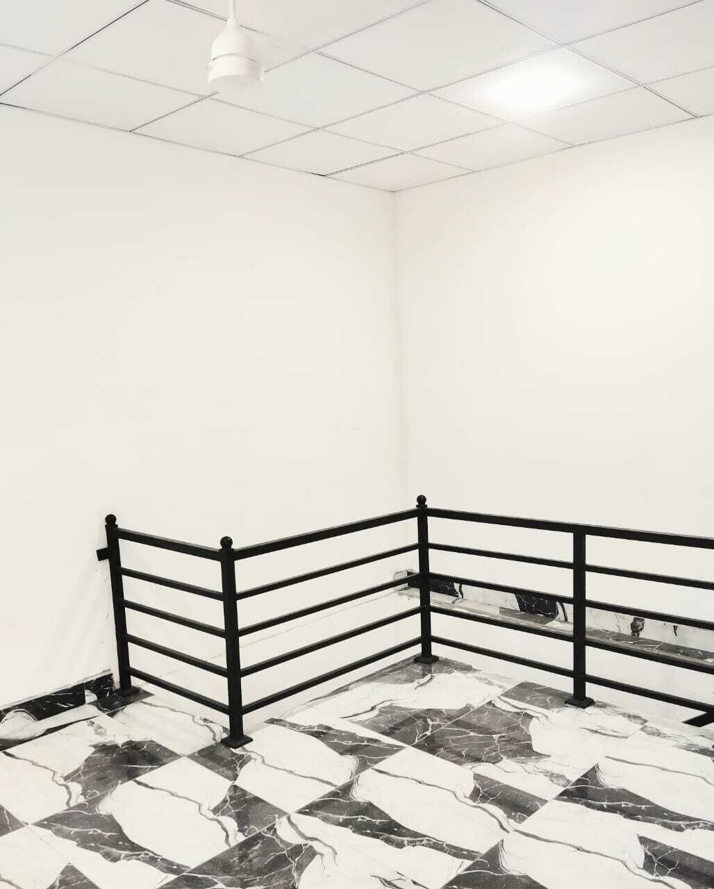Ein Zimmer mit einem Schachbrettmuster aus Marmor, einem schwarzen Metallgeländer und weißen Wänden.