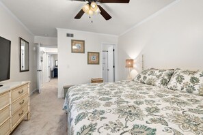A bedroom with a bed, dresser, ceiling fan, and framed pictures on the wall. - Southwinds Hideaway| Pool · Private Beach · 2BR AB (Atlantic Beach)