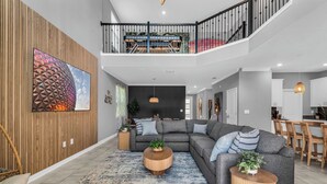 A modern living room with a sectional sofa, round coffee tables, and a large wall art piece. - Commercial Mario Arcade • Star Wars & Candy Rooms • 10 Mi Disney (Kissimmee)